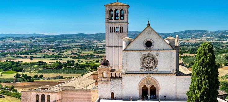 La Basilica di San Francesco si erge tra dolci colline e un cielo limpido, rappresentando un'importante opera religiosa.