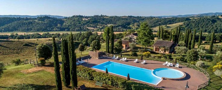 Una scena di una piscina immersa tra cipressi e paesaggi verdi, caratteristici della regione umbra.