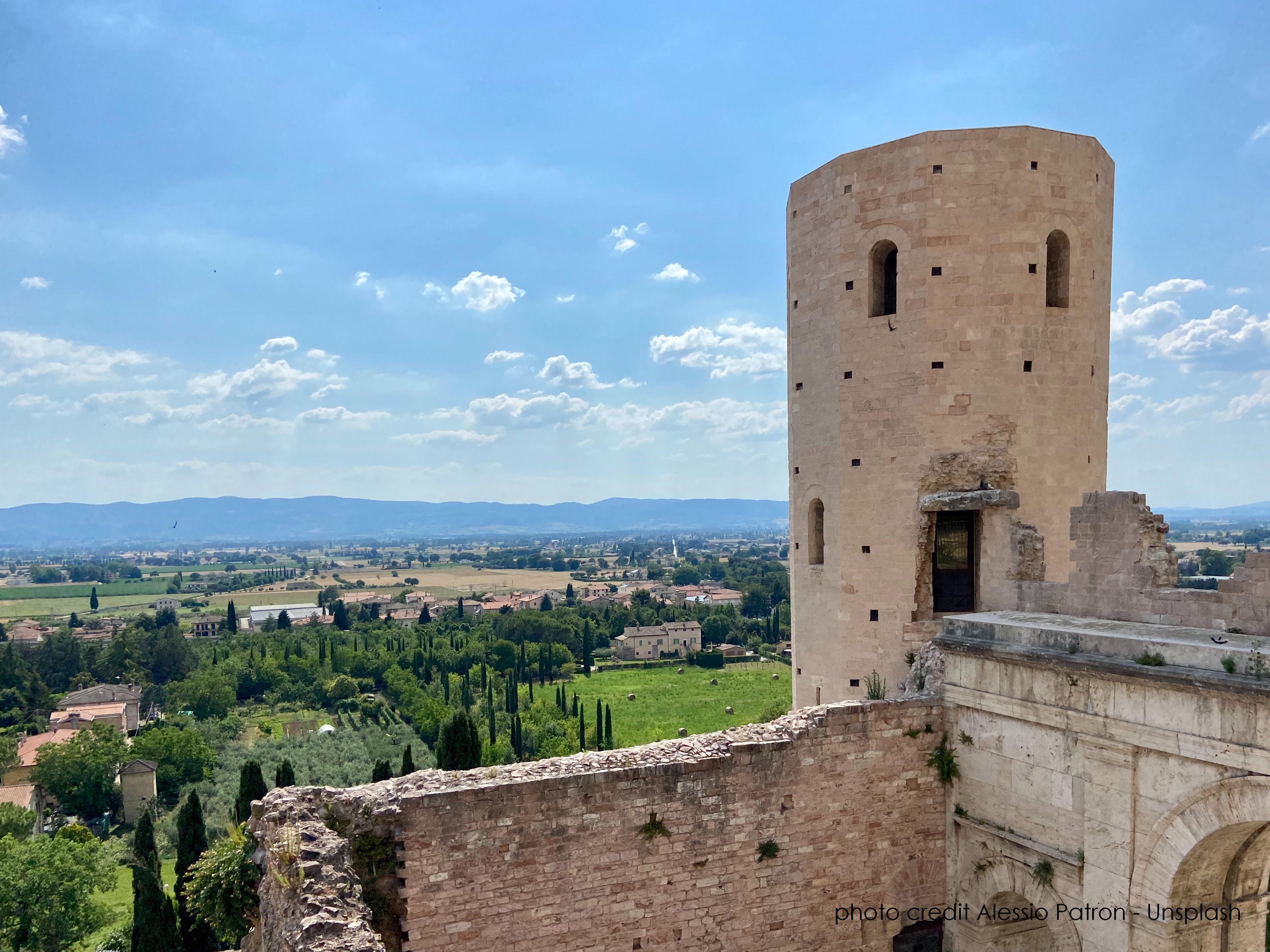 Una scena tranquilla della campagna umbra, con un dettaglio delle torri di Properzio e un cielo sereno.