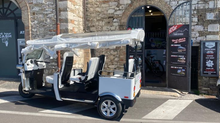 Un tuk-tuk parcheggiato davanti a un'agenzia di viaggi a Assisi.