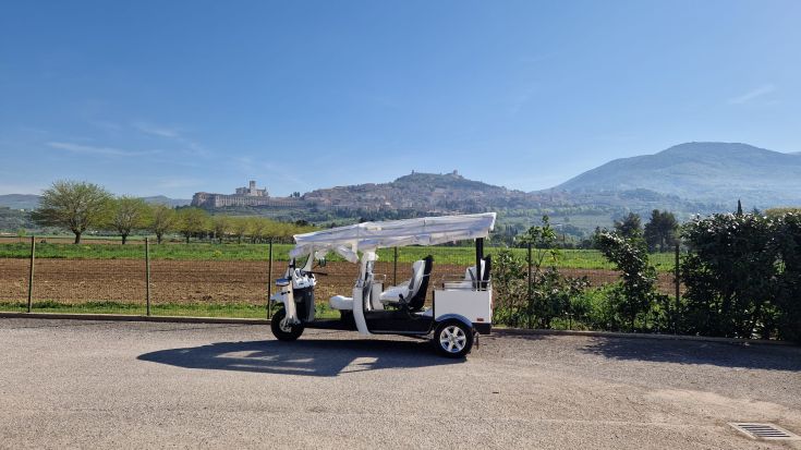 Un'ape calessino parcheggiata con un panorama della città in lontananza. Scopri la bellezza della campagna umbra!