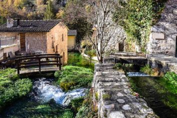 Un villaggio pittoresco con case in pietra e ruscelli che scorrono, immerso nella natura circostante.