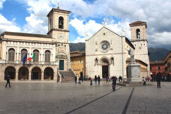 Piazza di Norcia , circondata da architettura storica e visitatori.