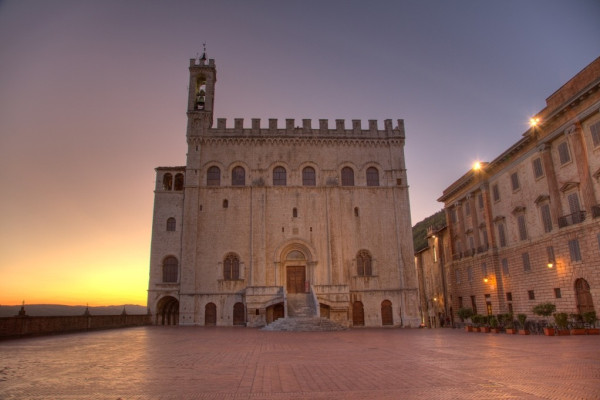 L'architettura del Palazzo del Capitano del Popolo al tramonto, in una piazza storica di Gubbio.