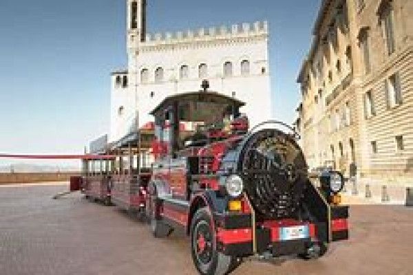 Un trenino colorato davanti a un suggestivo palazzo storico a Gubbio, ideale per visitare la città.