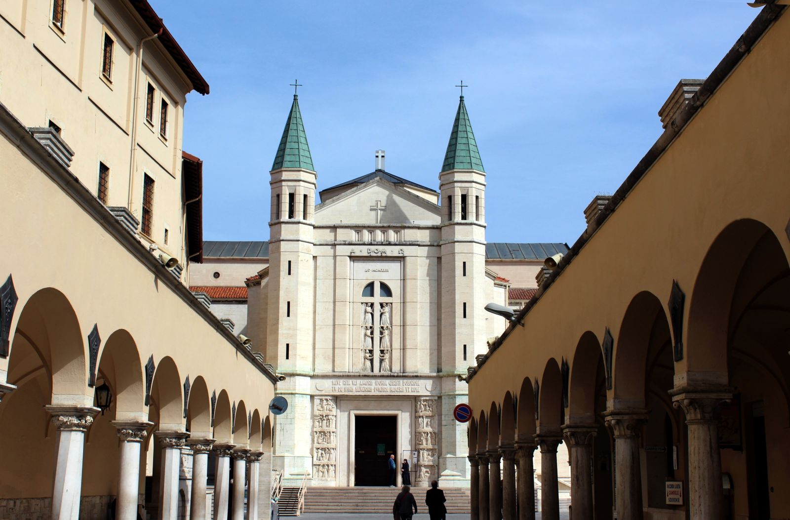 Chiesa di Santa Rita a Cascia con torrette, sotto un cielo tranquillo, circondata da archi che richiamano il passato.