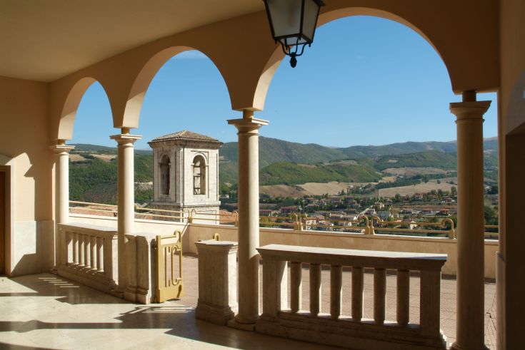 Panorama sulla campagna umbra visto da un balcone con colonne e archi.