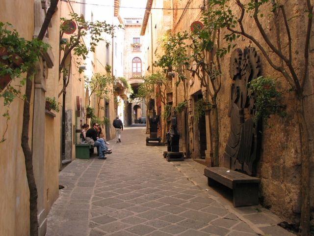 Un tranquillo vicolo di Orvieto, decorato con piante e dettagli architettonici. La scena trasmette un'atmosfera accogliente.