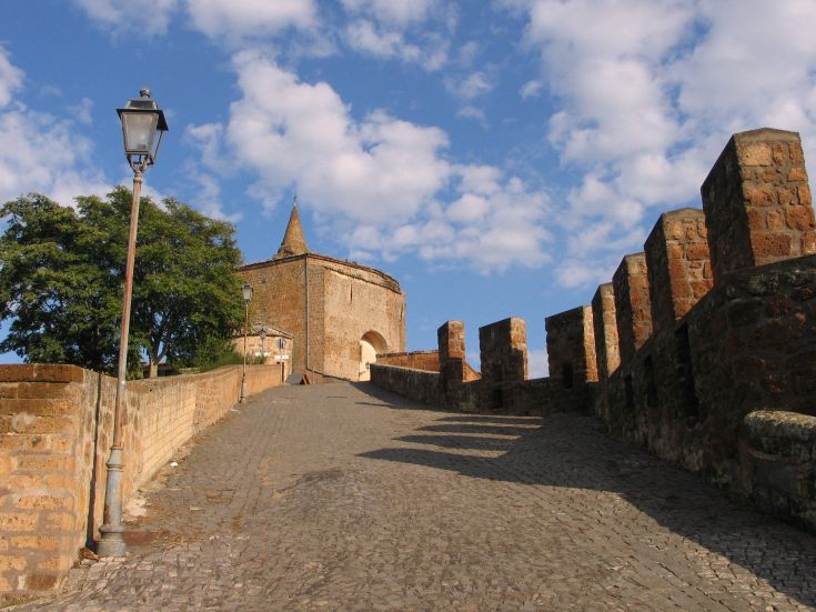 Una strada in pietra conduce a un vecchio palazzo, sbocciato sotto un cielo tranquillo e nuvoloso.