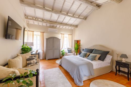 Camera semplice con soffitto a travi in legno, decorata con piante e colori neutri per un ambiente rilassato.