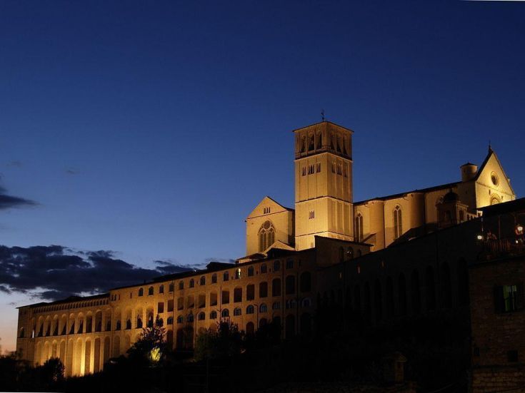 La Basilica di San Francesco di Assisi si distingue nel panorama notturno con la sua architettura storica ben visibile.