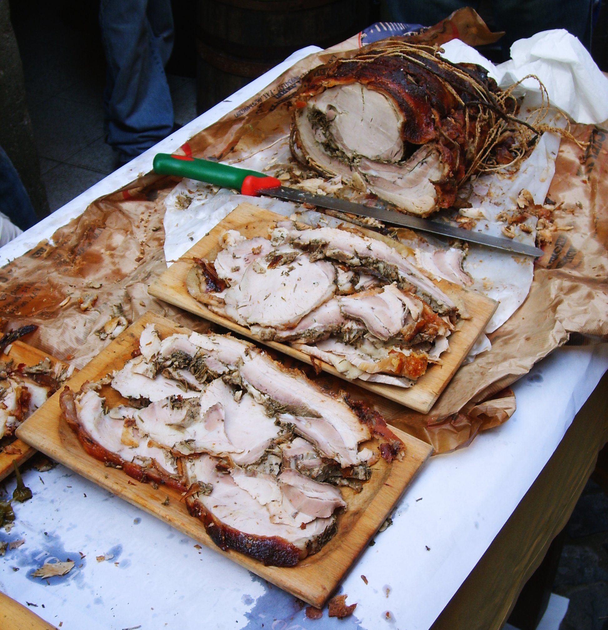 Porchetta pronta per essere servita distribuita su vassoi di legno, che rappresentano la tradizione culinaria della regione.