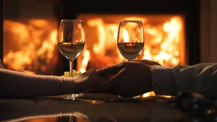 Una serata intima con calici di vino e un camino acceso in un accogliente soggiorno.