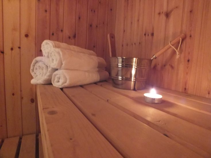 Interno della sauna con asciugamani arrotolati e una candela accesa che crea un'atmosfera tranquilla.