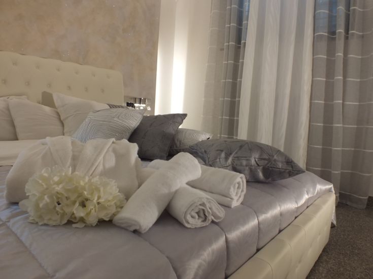 Camera semplice e moderna con letto, cuscini e asciugamani disposti con cura, ideale per il relax.