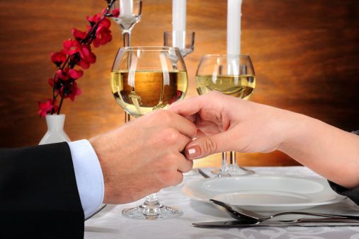 Un momento romantico con un brindisi a lume di candela. Mani unite sopra il tavolo.