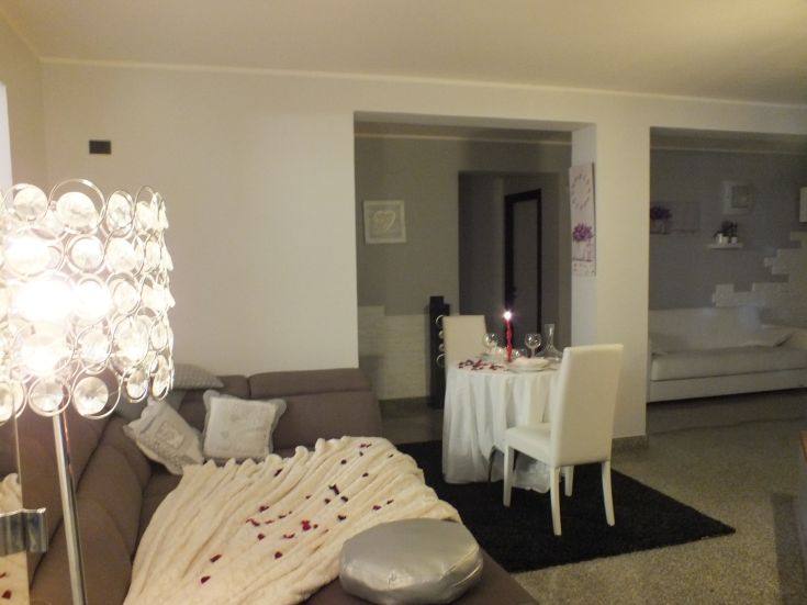 Un soggiorno accogliente con decorazioni floreali e un tavolo per cene intime, ideale per trascorrere momenti speciali.