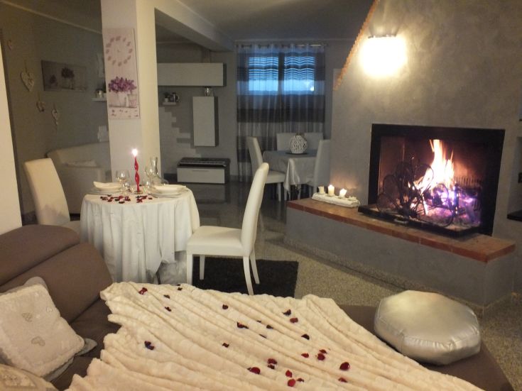 Un soggiorno confortevole con camino acceso, arredato per una cena intima.