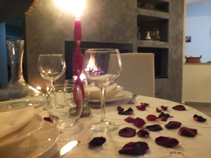 Un'atmosfera accogliente con petali di rosa sparsi su un tavolo e una candela accesa al centro.